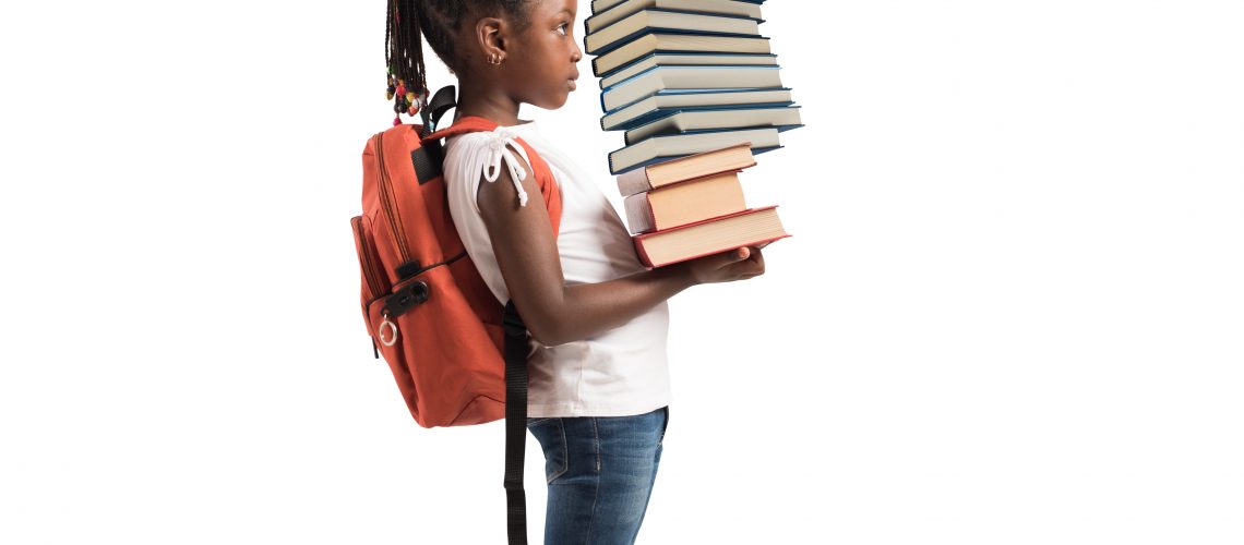 Child with backpack and a study books pile